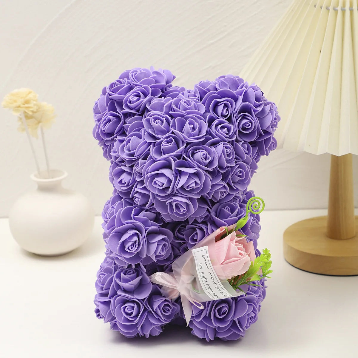 Un bouquet de roses en mousse douce violettes en forme de ours en peluche, à côté d'une lampe de couleur crème.