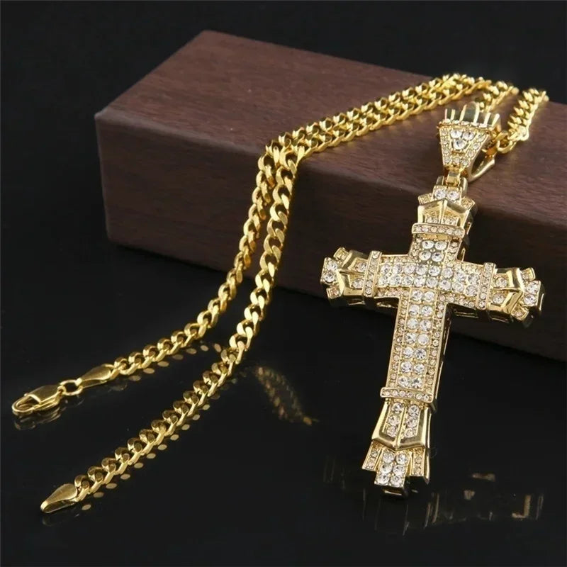 A gold-colored retro Christian cross amulet necklace lying on a dark surface.