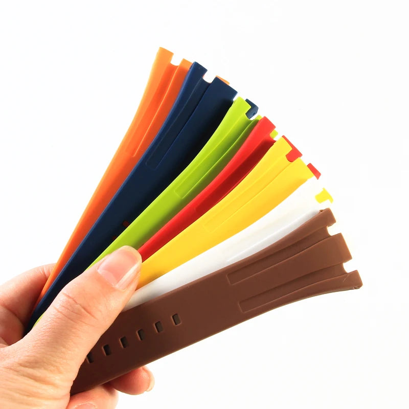 A hand holds a fan of colorful silicone watch bands, including orange, blue, green, and yellow.