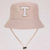A light beige sun hat with a large gold letter T embroidered on the front.