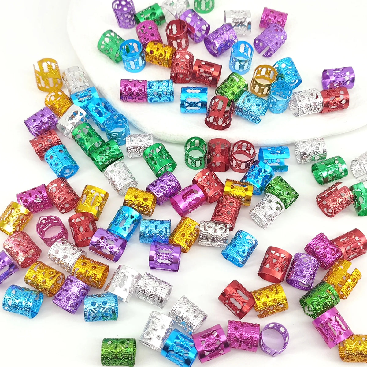 A collection of multicolor dreadlock hair rings and beads in various shades including purple, green, blue, and gold.