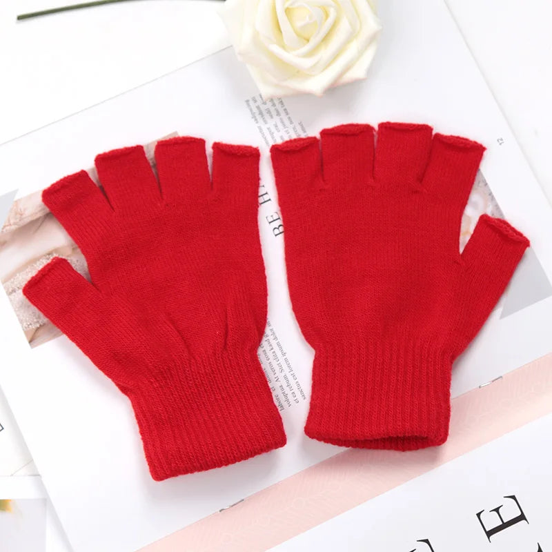 A pair of bright red knit half finger gloves lying on a white surface next to a white rose.