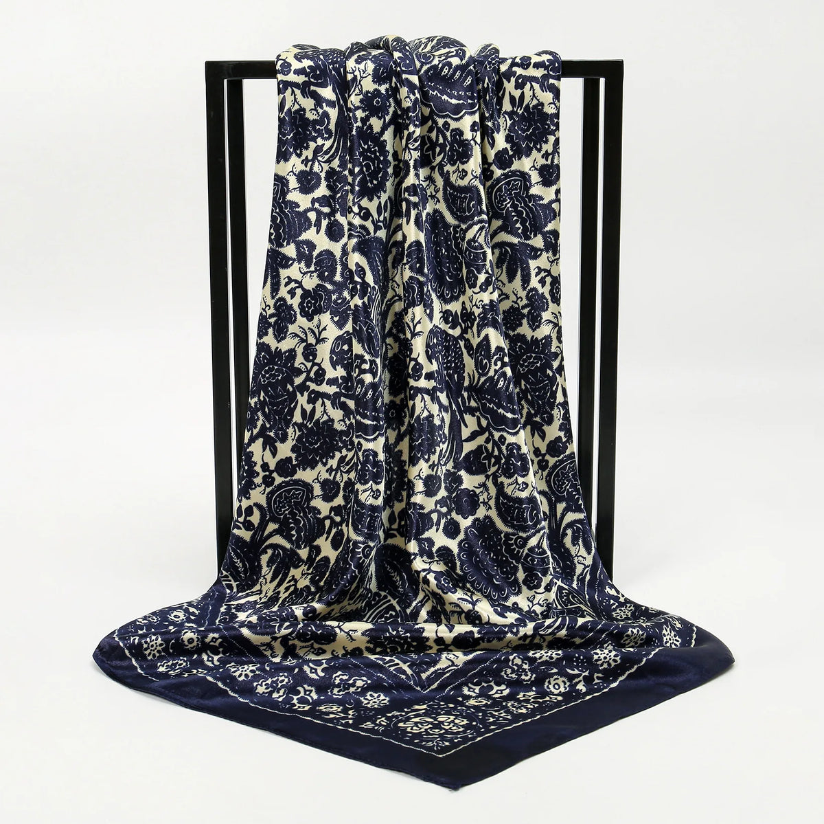 A dark blue and cream patterned silk scarf draped on a black display stand.