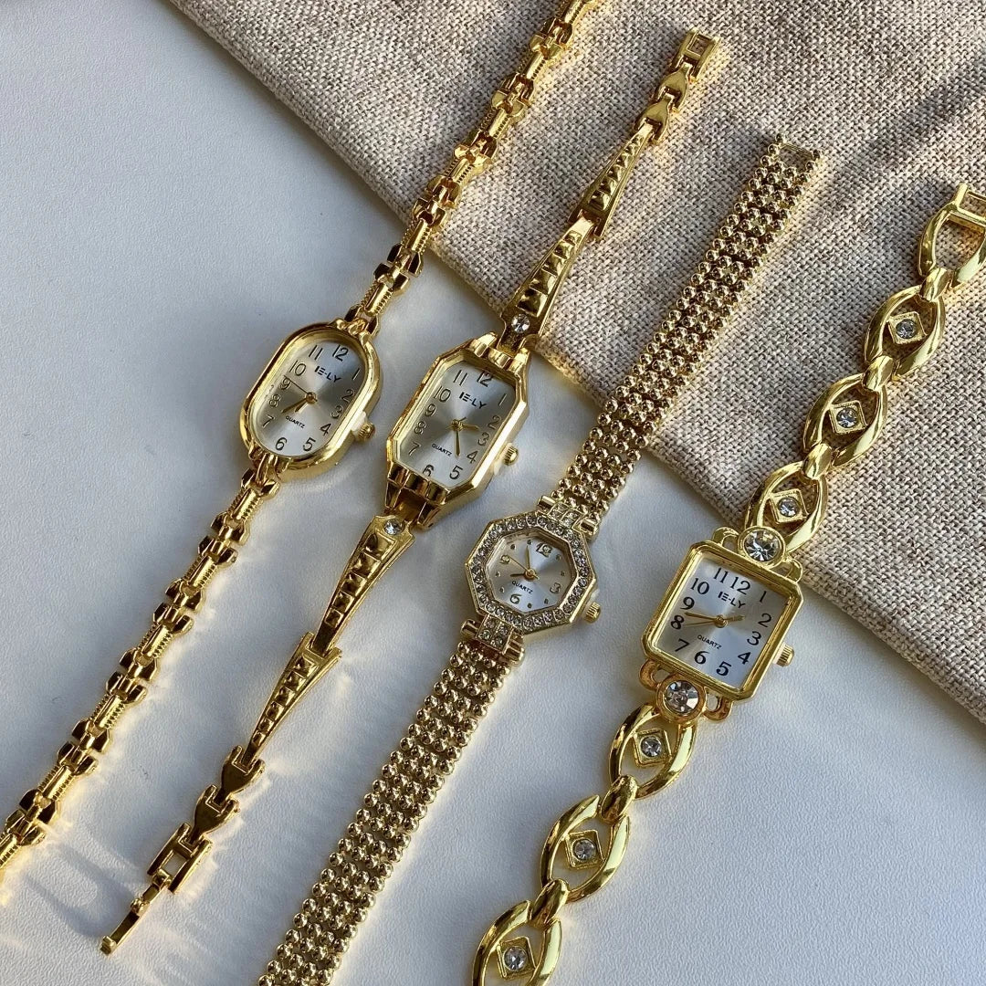 A collection of gold-toned quartz fashion wristwatches displayed on a neutral fabric background.