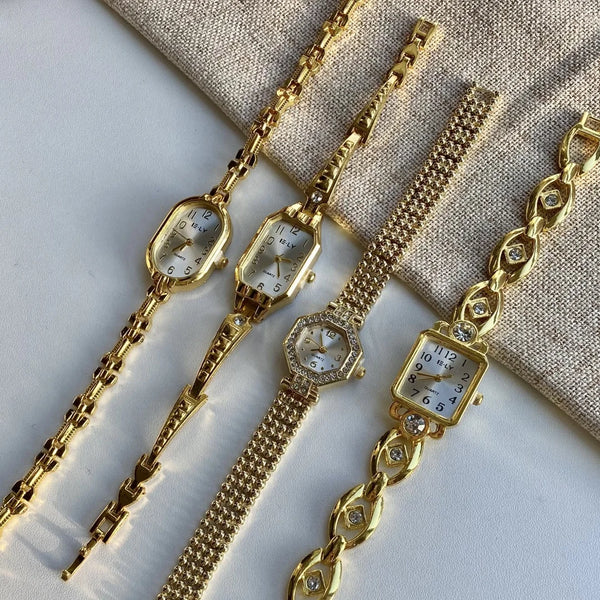 A collection of gold-toned quartz fashion wristwatches displayed on a neutral fabric background.