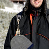 A person wearing a black jacket is holding a metal glove clip holder.