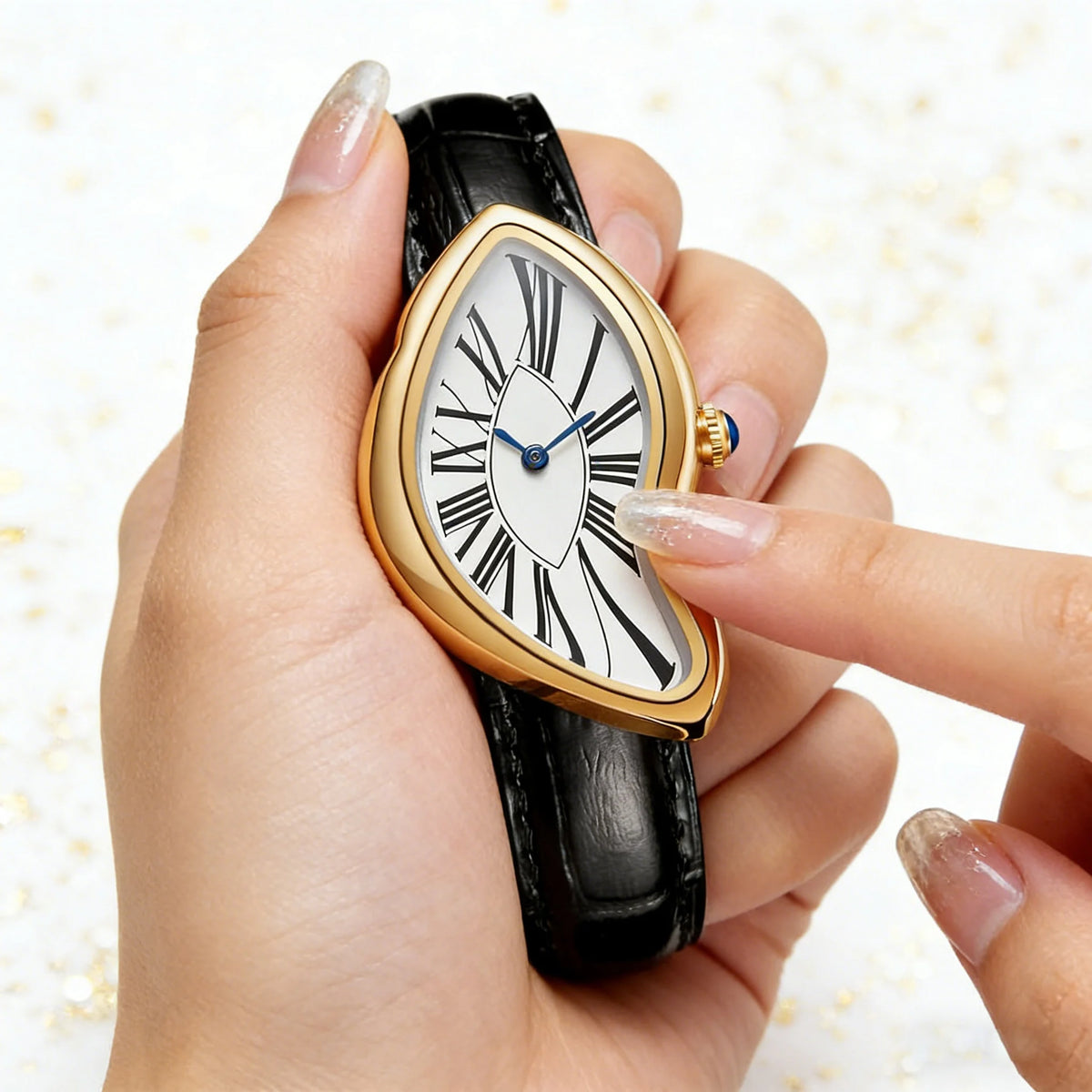 A hand holds a gold-toned watch with an irregular face and black strap, showing the white dial and blue hands.