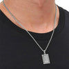 A silver letter pendant necklace with an E charm worn around the neck against a black shirt.