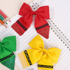 A set of colorful fabric bows, including red, yellow, and green, displayed on lined paper.