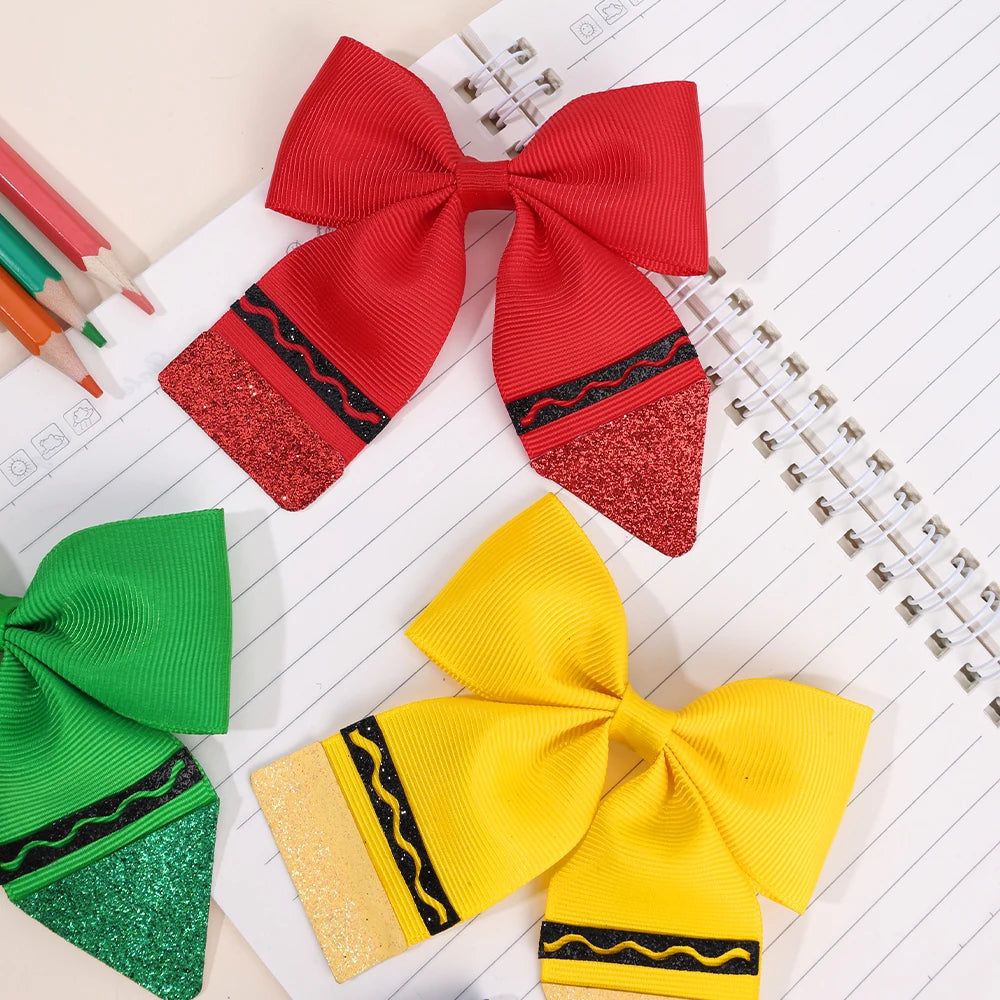A set of colorful fabric bows, including red, yellow, and green, displayed on lined paper.