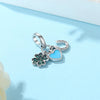 A silver family tree charm necklace featuring a heart pendant and a floral charm on a light blue background.