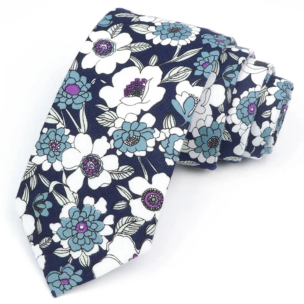 Une pile de cravates en coton à motifs floraux élégants avec des fleurs blanches et violettes sur fond bleu foncé.