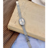 Une montre en quartz argentée avec un bracelet métallique repose sur un vieux livre.