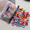 A pile of colorful elastic hair bands in various shades including pink, yellow, blue, and red on a white surface.