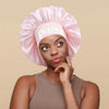 A woman wearing a pink satin sleep bonnet with a white Pisces wrap band.