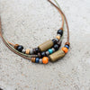 A set of boho vintage wood and stone beads strung on natural twine, laid on a light gray surface.