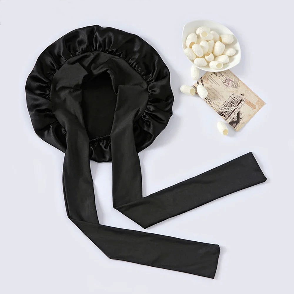 Black silk sleep bonnet with a matching fabric tie and a bowl of white hair rollers