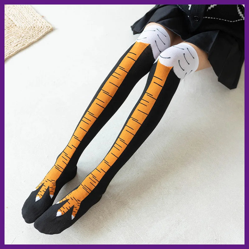 Black socks with orange chicken print detailing on the foot and leg, worn under a black garment.
