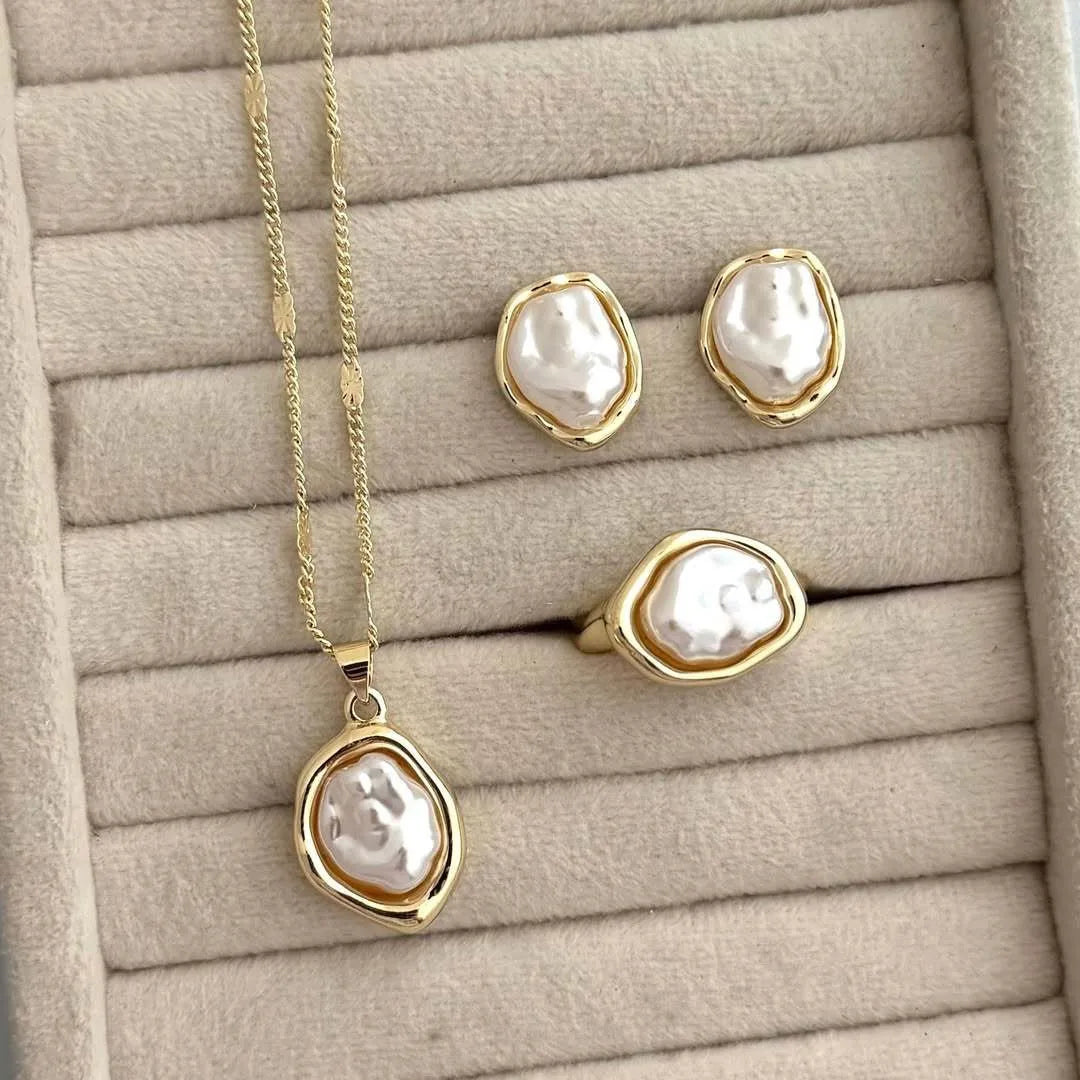 A set of golden baroque imitation pearl earrings and a pendant displayed on a neutral background.