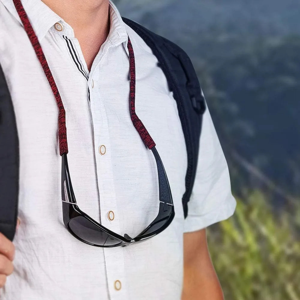 A person wearing a white shirt with a black and red lanyard holding a pair of sunglasses.