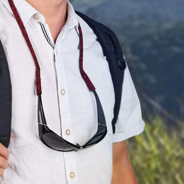 A person wearing a white shirt with a black and red lanyard holding a pair of sunglasses.