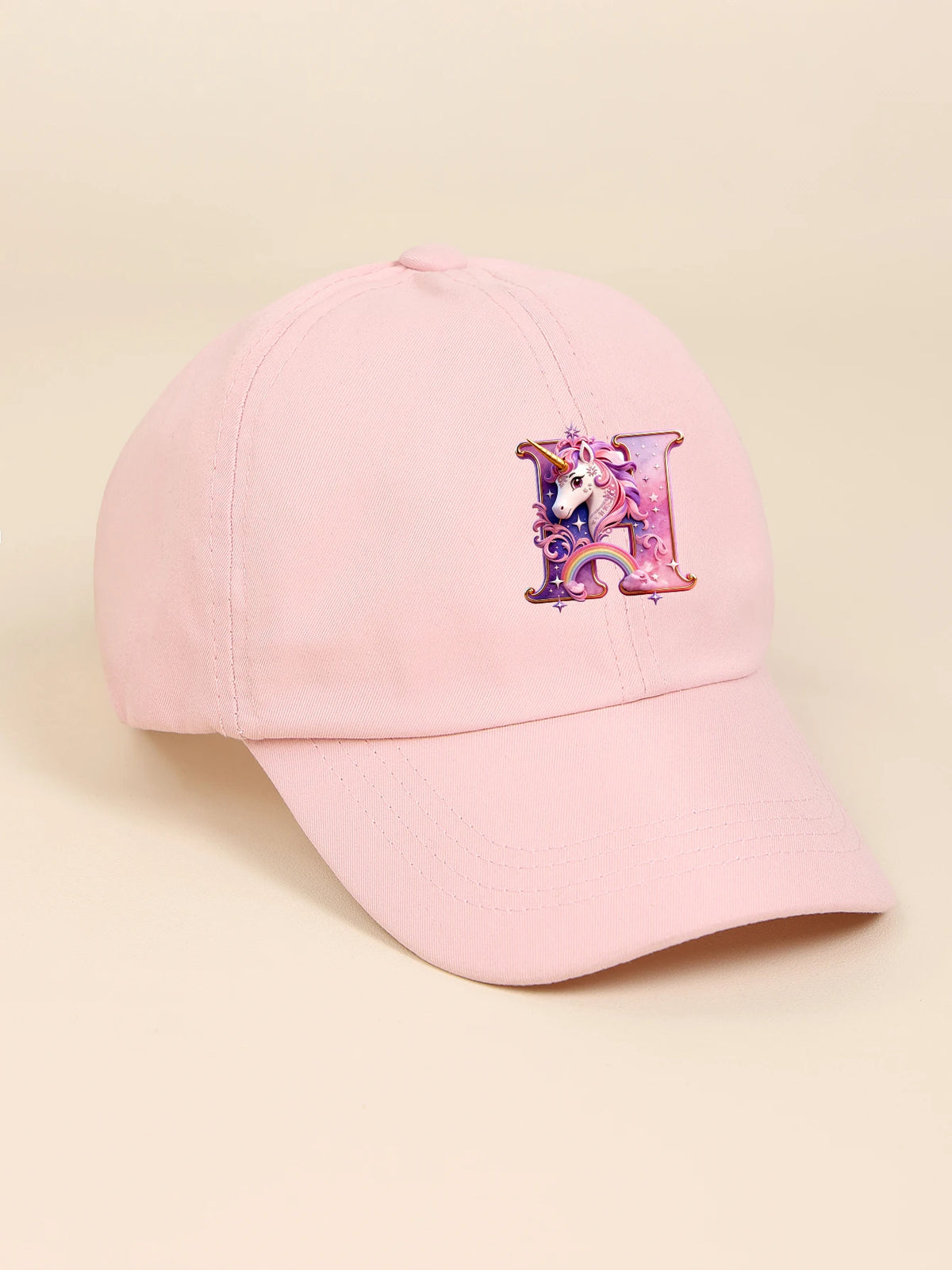 Pink baseball cap featuring a purple unicorn letter design
