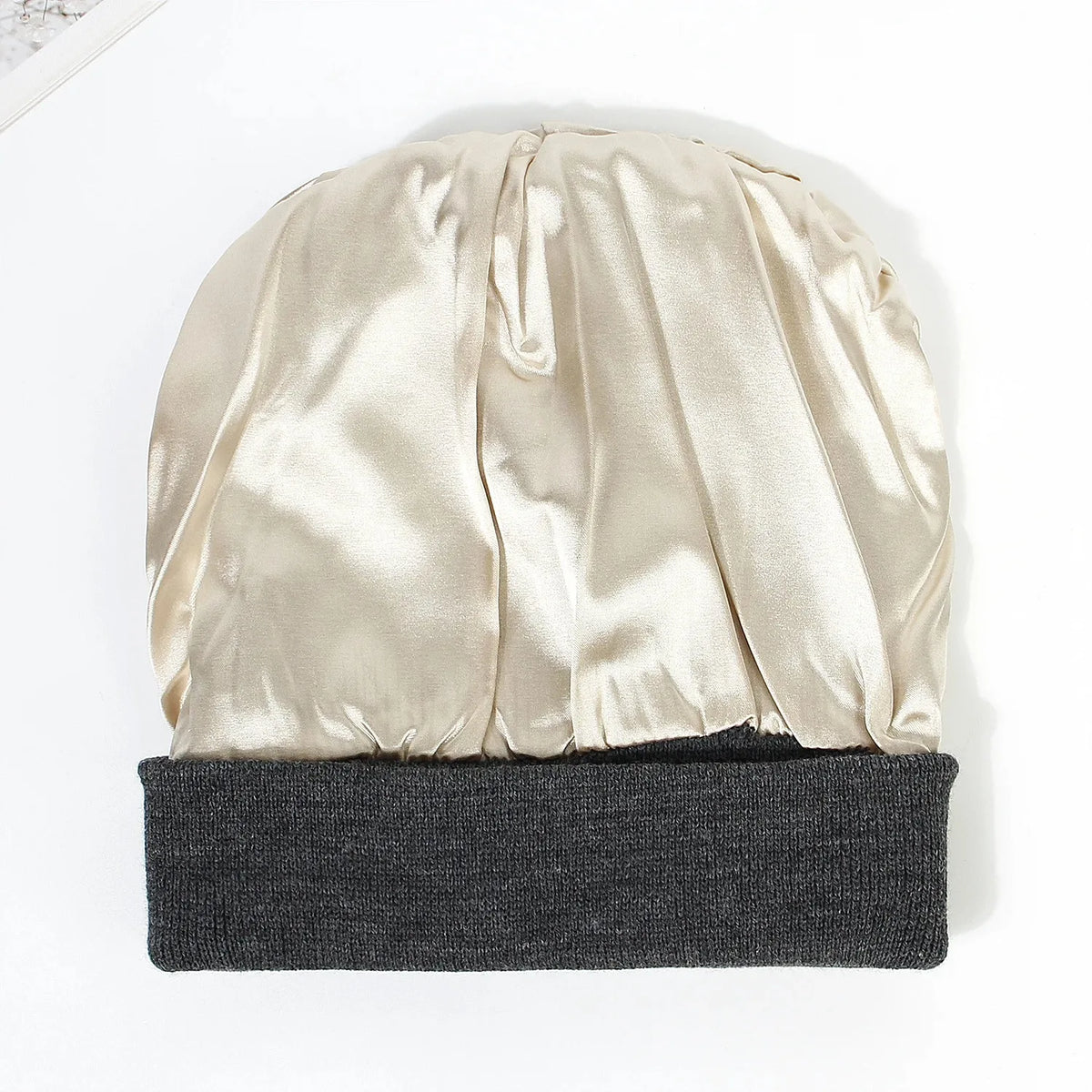 A beige satin lined beanie hat displayed on a white background.
