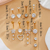 A collection of gold dangle curved belly piercing jewelry featuring heart and flower designs with various lengths.