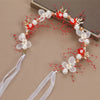 Elegant floral wreath headband featuring white and red flowers and pearl accents on a dark background.