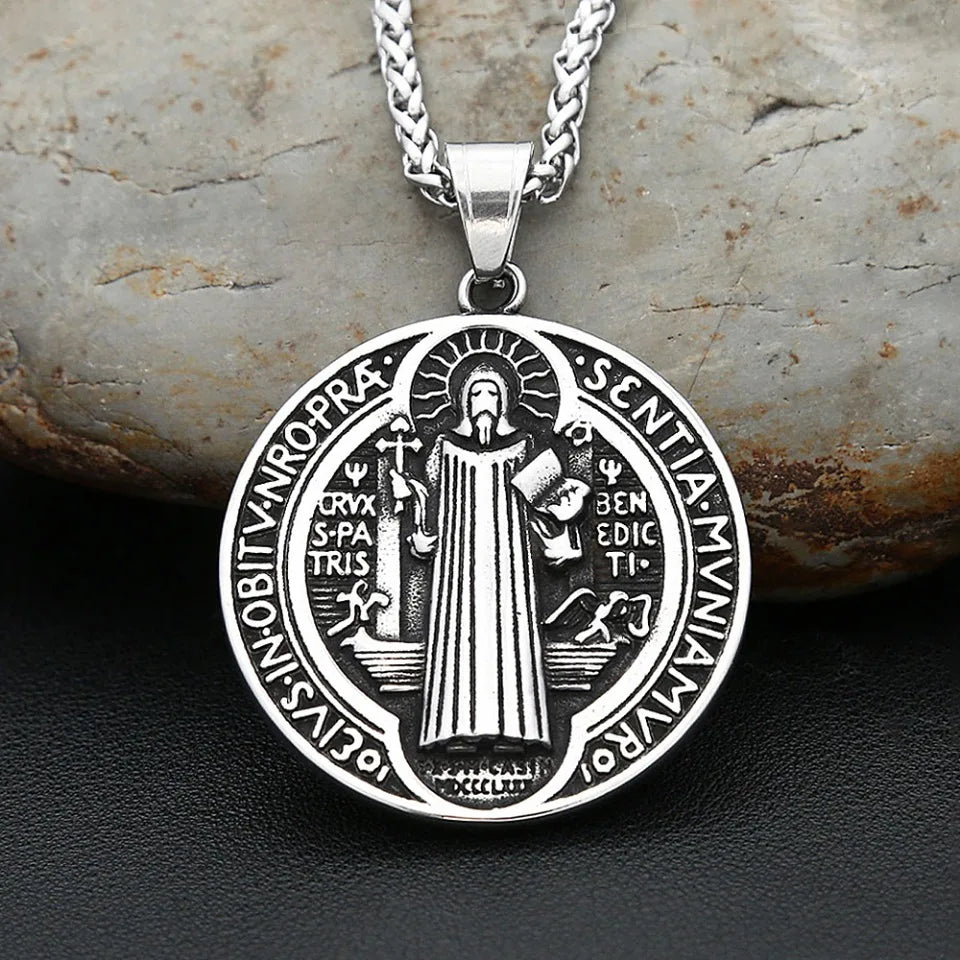 Silver pendant necklace featuring an oval design with Latin text and a depiction of Saint Benedict.