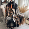 A black and beige patterned luxury plaid cashmere feel scarf and shawl wrap displayed on a white chair.