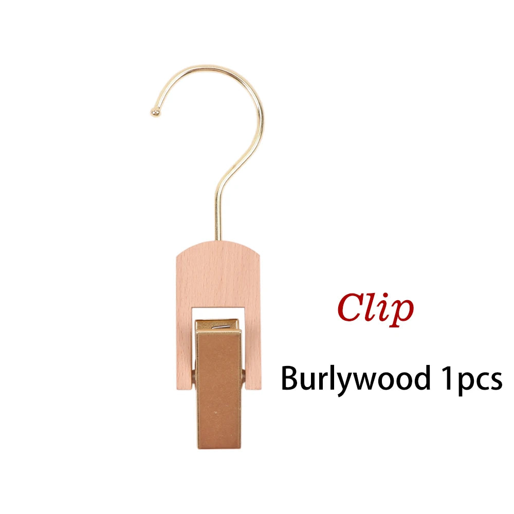 A wooden clip with a gold-colored hook used to hold wigs or hair extensions.