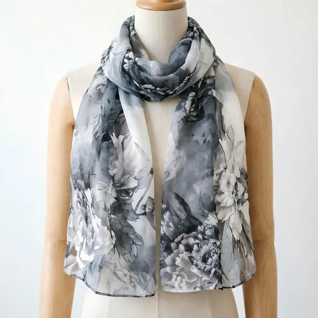 Une femme modélise un élégant châle en soie floral dans des tons de gris et de blanc.