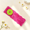 A pink lace headband with a lime green polka dot button, surrounded by white daisy flowers.