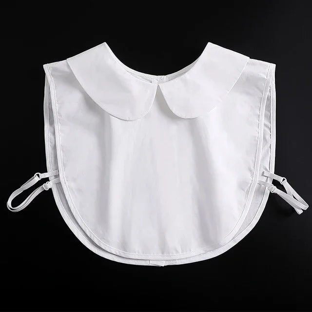 A white blouse with a fashionable false collar and detachable neckline shown against a black background.