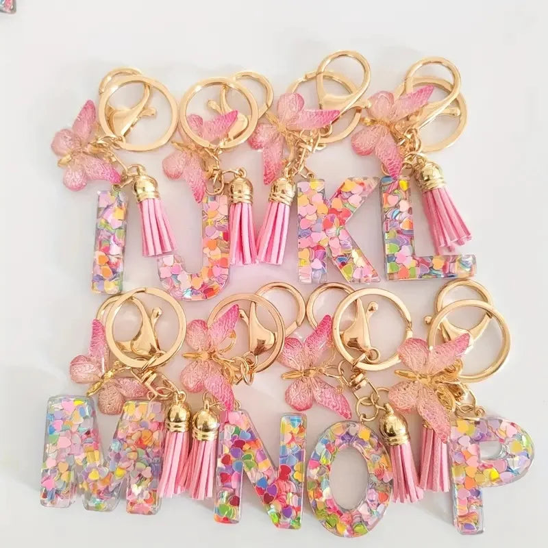 Alphabet letter acrylic keychains in various colors with pink butterfly tassels