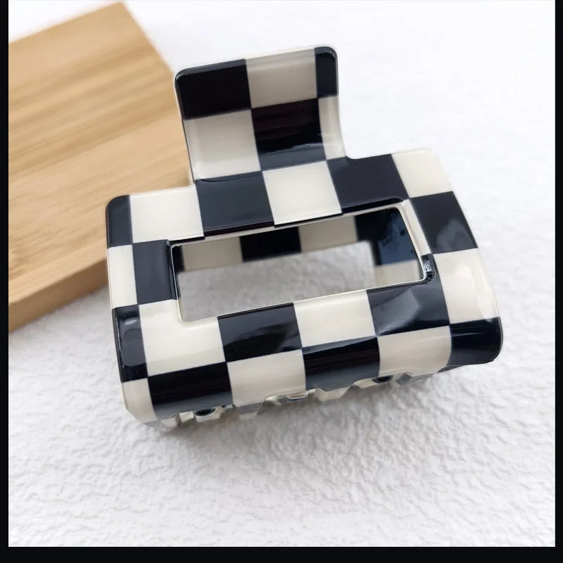 A black and white checkered rectangle hair claw clip resting on a light surface.