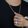 Gros plan d'une femme portant un collier pendentif en croix serti et une bague en diamant sur un t-shirt noir.