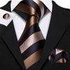 A close-up of a men's silk jacquard tie featuring diagonal stripes in black and bronze on a black suit jacket.