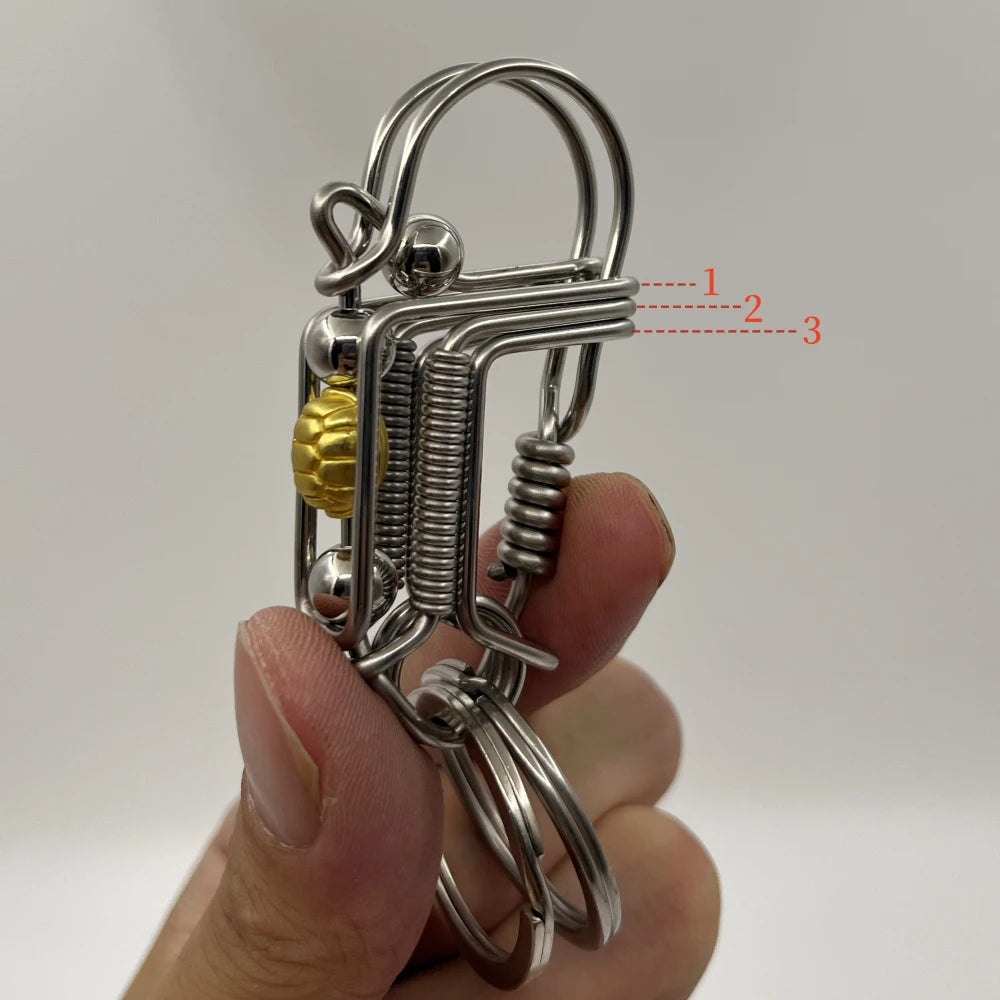 Un porte-clés mécanique en acier inoxydable avec une boucle et un mécanisme à ressort tenu dans une main.