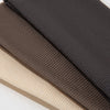 Three solid color fashion headbands stacked diagonally in shades of dark gray, brown, and beige.