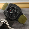 A black sports watch with a olive green strap and a silver chain displayed on a dark surface.