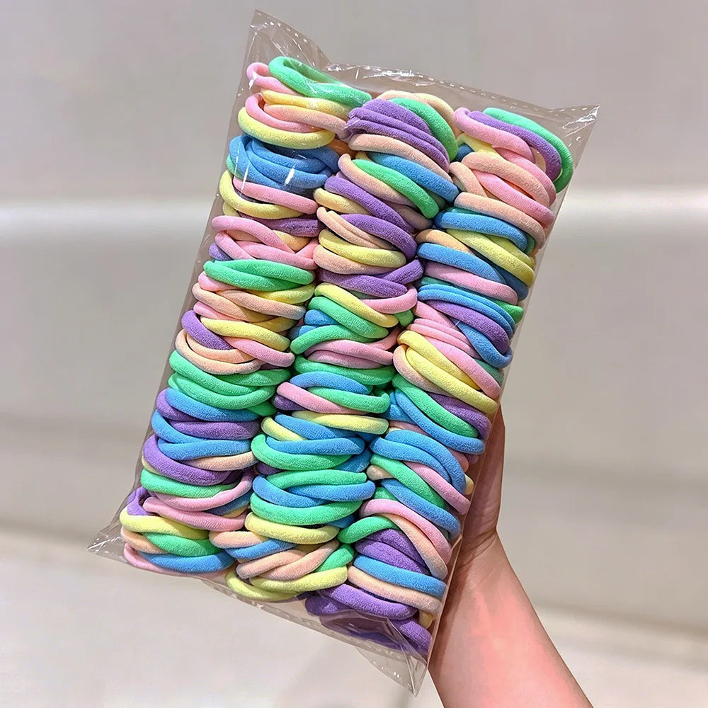 A bundle of multicolored elastic hair ties in various shades of pink, purple, blue, and green.