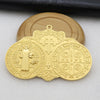 A gold-colored Saint Benedict protection medal with an ornate design and a wooden background.