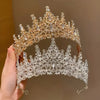 Primer plano de una elegante tiara de pedrería barroca para novia, sostenida por una mano.