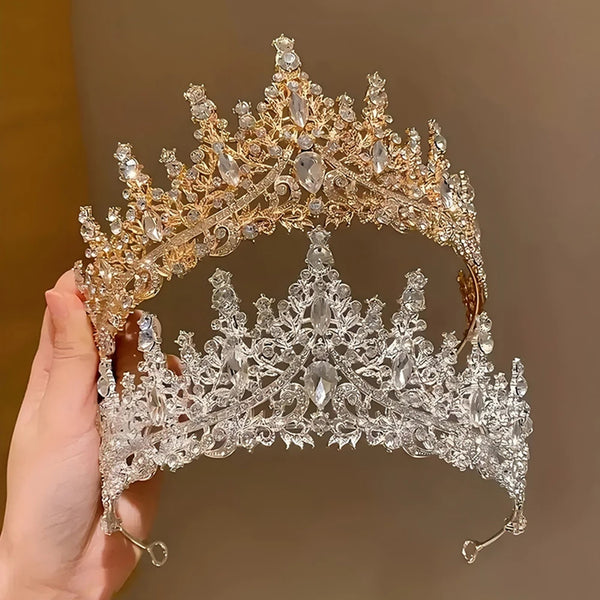 A close-up of an elegant Baroque rhinestone bridal tiara headband being held by a hand.