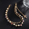 Gold chain necklace with white pearls and a cross pendant on a black background
