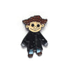 Une épingle émaillée noire représentant un personnage de dessin animé aux cheveux bruns bouclés et aux bottes bleues.