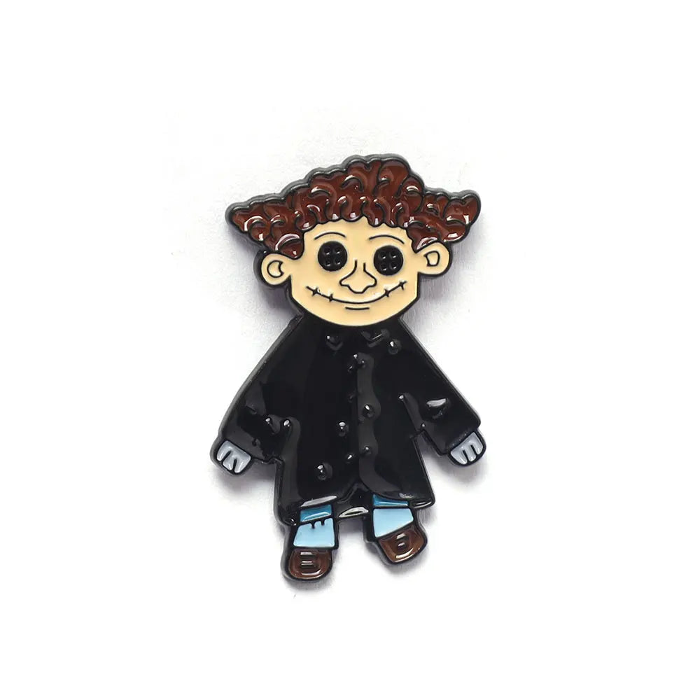 Une épingle émaillée noire représentant un personnage de dessin animé aux cheveux bruns bouclés et aux bottes bleues.