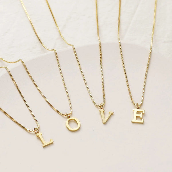 A set of delicate gold-plated initial letter necklaces featuring the letters O, L, V, and E.